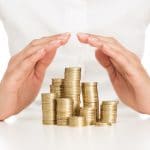 Savings protection, close up of female hands covering stack of g